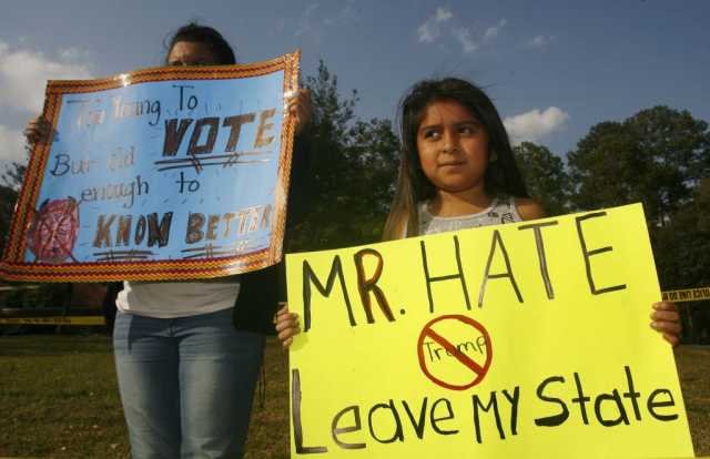 A young demonstrator holds up a sign protesting Republican presidential candidate Donald Trump down the street from a political campaign rally at the Valdosta State University Complex in Valdosta, Georgia, February 29, 2016. REUTERS/Philip Sears